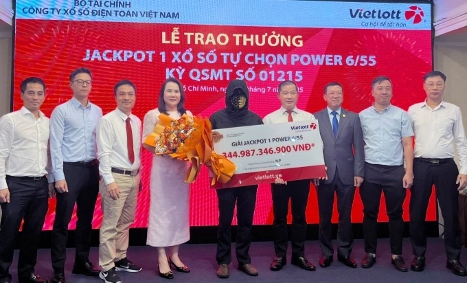 Ông N.P. (đeo mặt nạ) nhận thưởng từ đại diện Vietlott chiều 22/7. Ảnh: Minh Anh